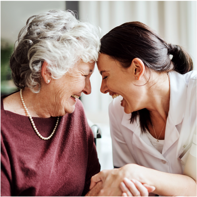 memory care community residents laughing and touching foreheads with woman