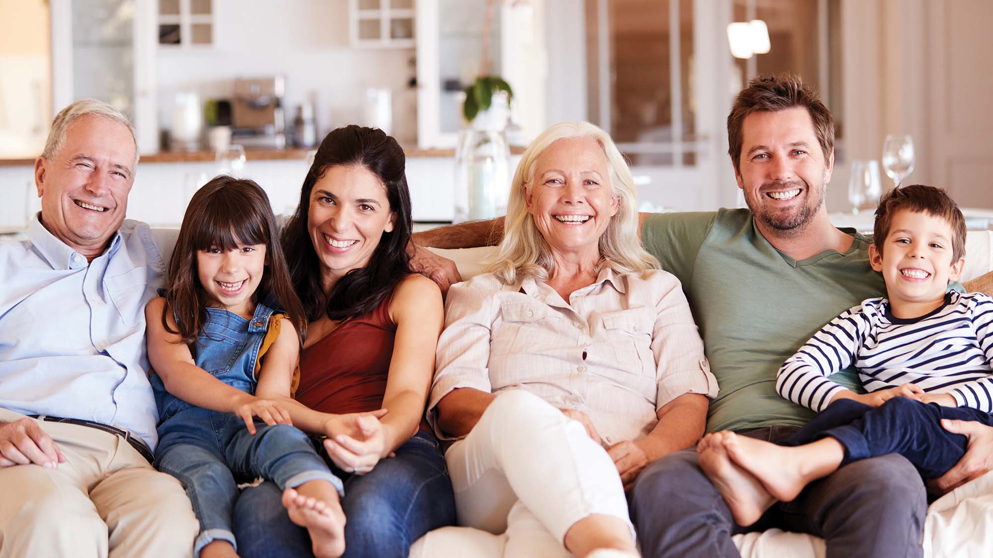 Senior living family on couch with grandparents, adult children and grand children