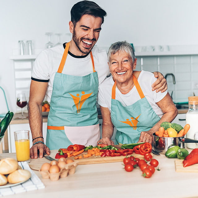 Senior living community resident laughing with cooking class teacher