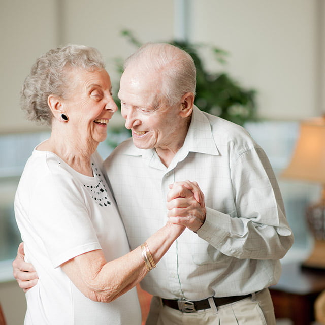 two senior living community residents dancing together