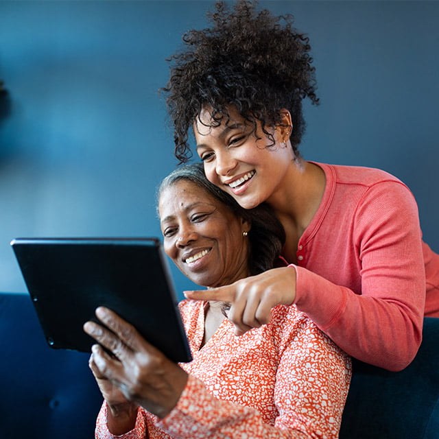 senior woman taking a virtual tour of a senior living community on a tablet with her daughter