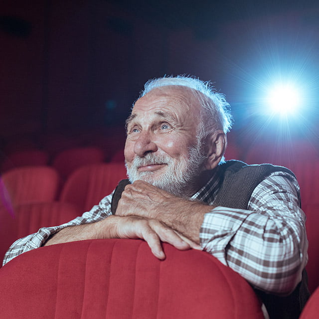 senior man watching a movie in a theater at a senior living community