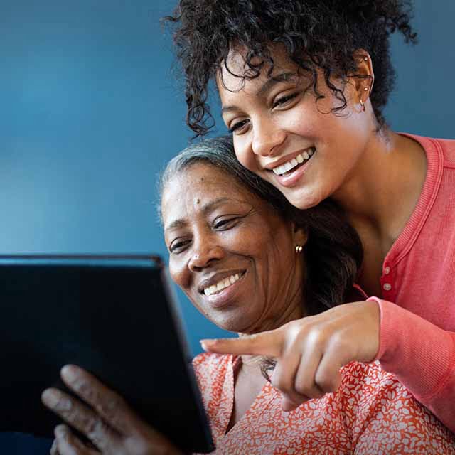 Senior woman with daughter reading senior living community blogs on a tablet