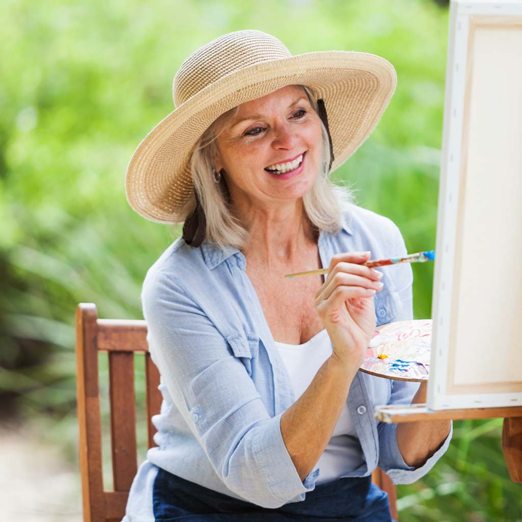 Senior woman painting on canvas at assisted living community