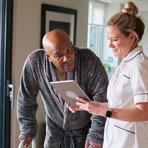 Senior living resident with walker talking to nurse showing him a tablet