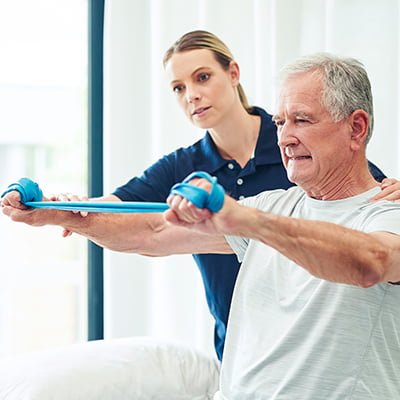 Senior living resident exercising with help from staff member